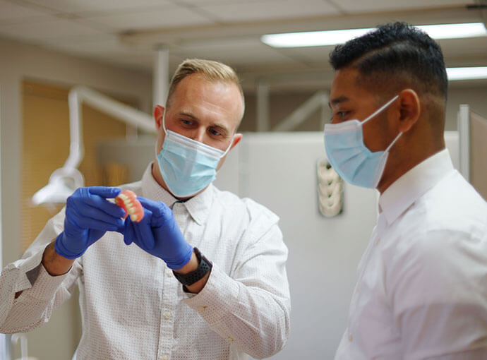 Michael Holden and Josh Williams taking a look at a denture